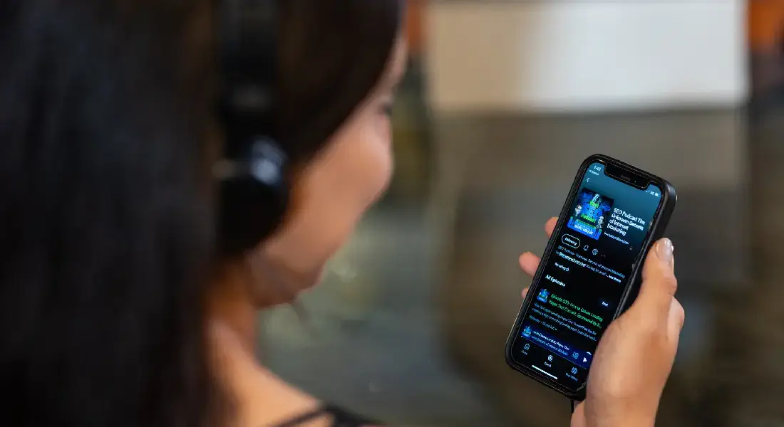Local Internet Marketing Houston | Girl Engaged in SEO Learning: Listening to Matt Bertram's Podcast via Headphones, Checking Phone