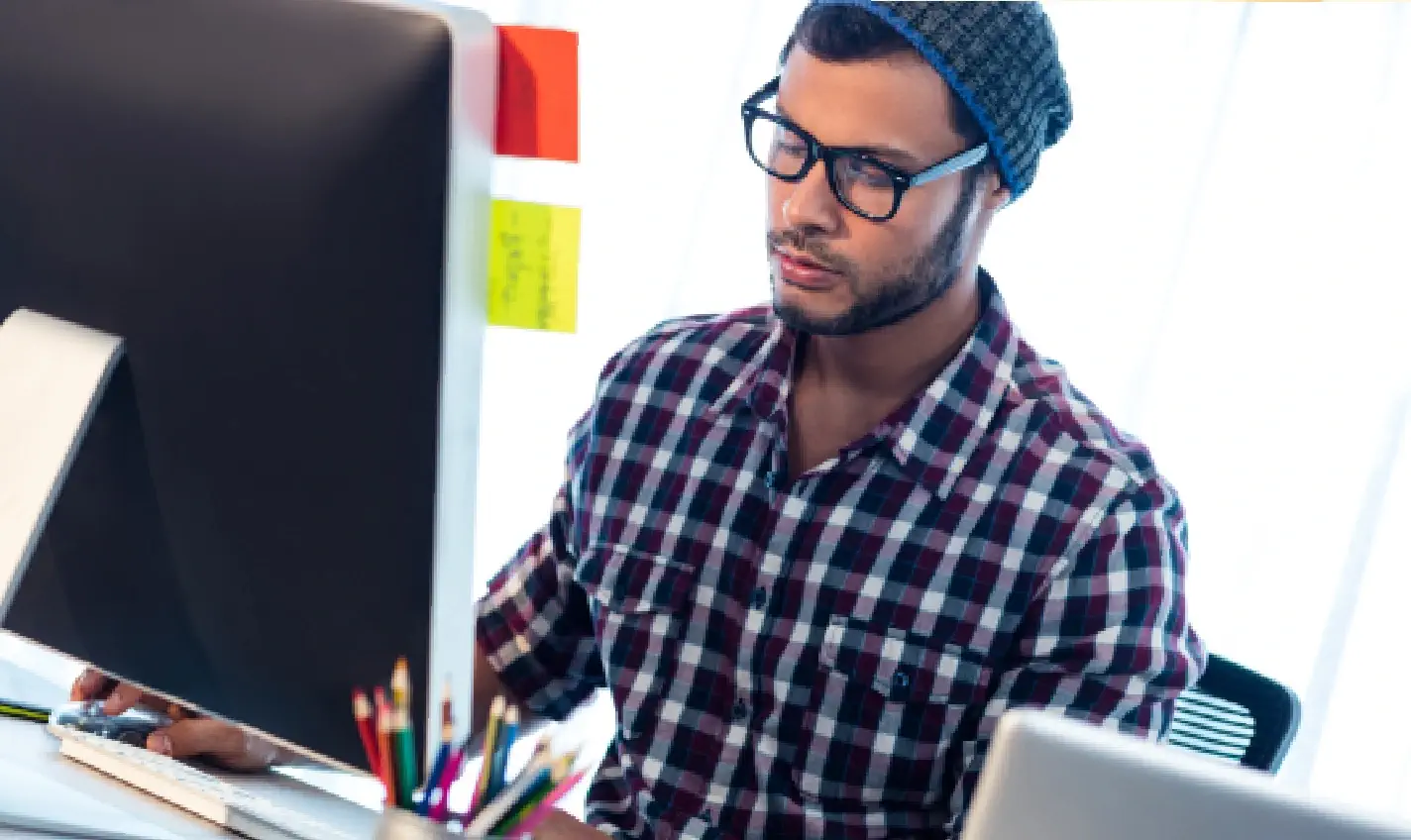 A man sits in front of a computer, surrounded by monitors and technology, representing the role of a webmaster in business success