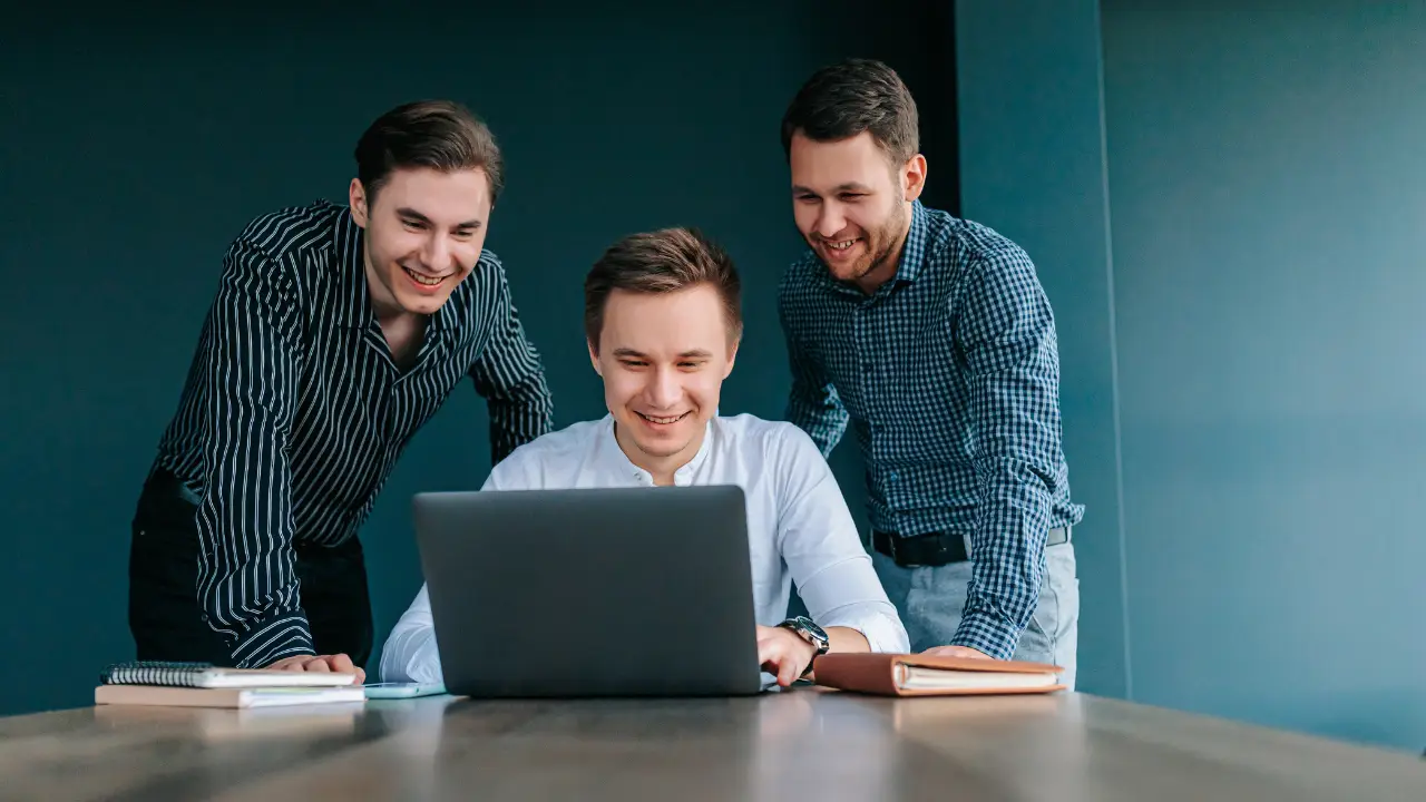 professionals in a meeting room, reviewing charts and analytics on a laptop