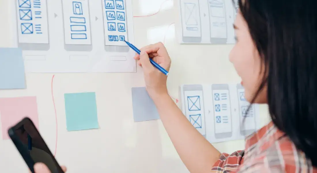 Website information taxonomy - woman planning website UX and UI on a whiteboard