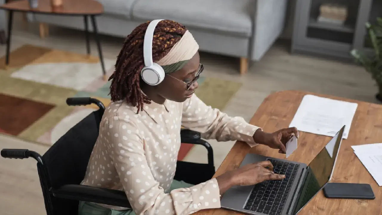 A woman in a wheelchair engages with her laptop, exploring a website that exemplifies accessible web design