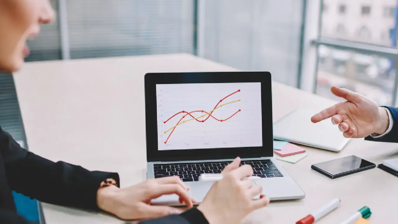Hand pointing to a laptop screen featuring a line graph representing B2B SEO strategies