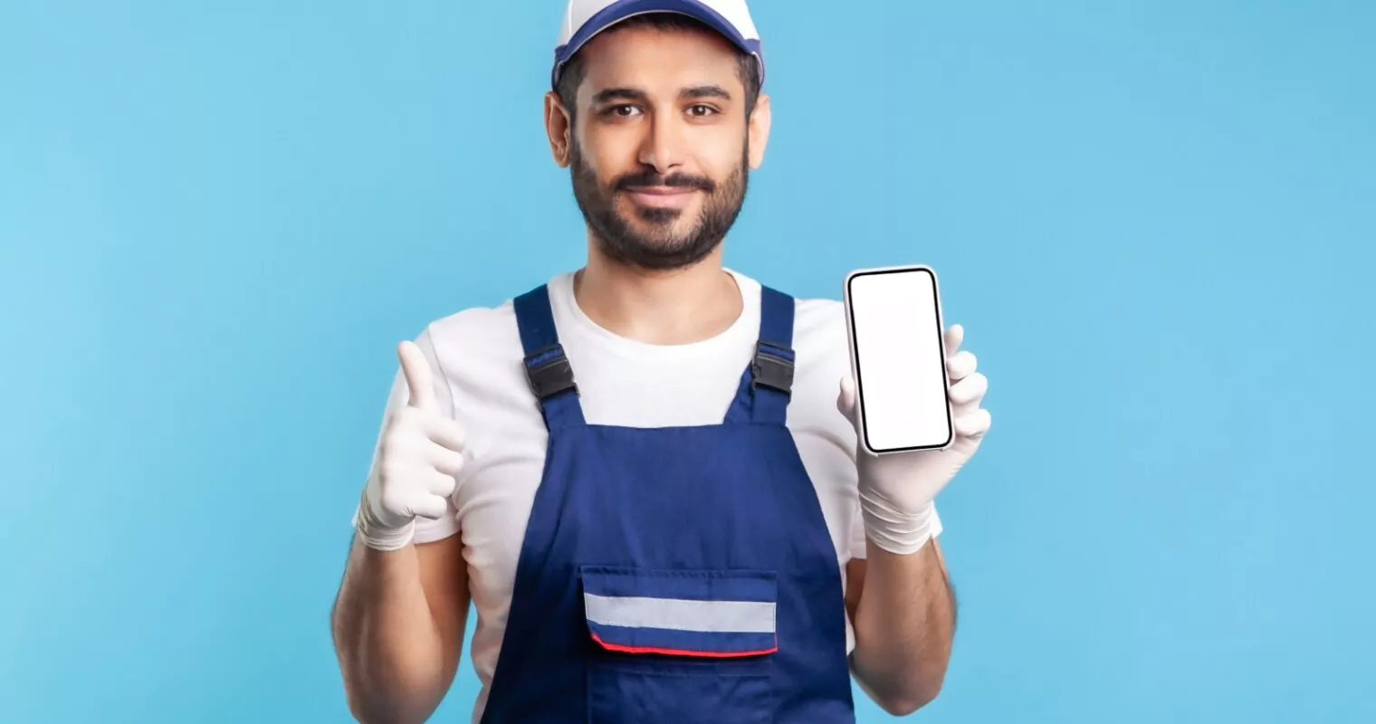 A plumber in action, holding a mobile phone, illustrating the importance of Local SEO for plumbing businesses.